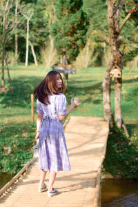 Portrait of young woman standing against trees