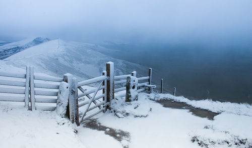 High angle view of snow covered railing on mountain against sky