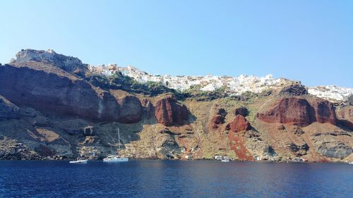Rock formations in sea against clear blue sky