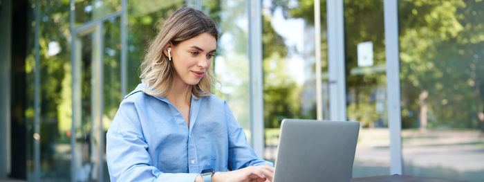 Young woman using laptop while sitting on table