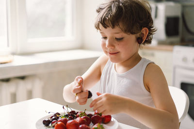 Cute beautiful little boy eating fresh cherry and strawberry.