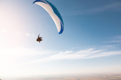 Low angle view of person paragliding against sky during sunset