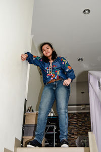 Portrait of young woman standing against wall at home