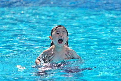 Boy screaming in pool during sunny day