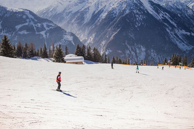 People skiing on snow covered against mountain