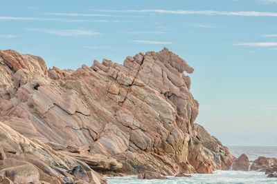 Rock formations on sea shore against sky