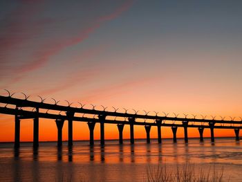 Pier over sea against sky during sunset