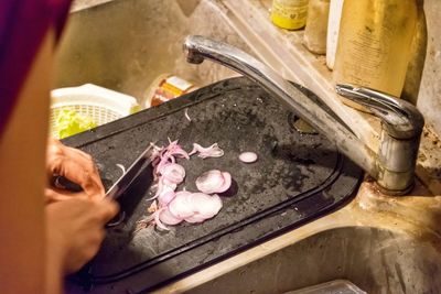 Cropped image of woman chopping onions on cutting board in kitchen
