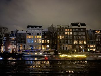 Illuminated buildings on canal  in city at night during christmas in amsterdam
