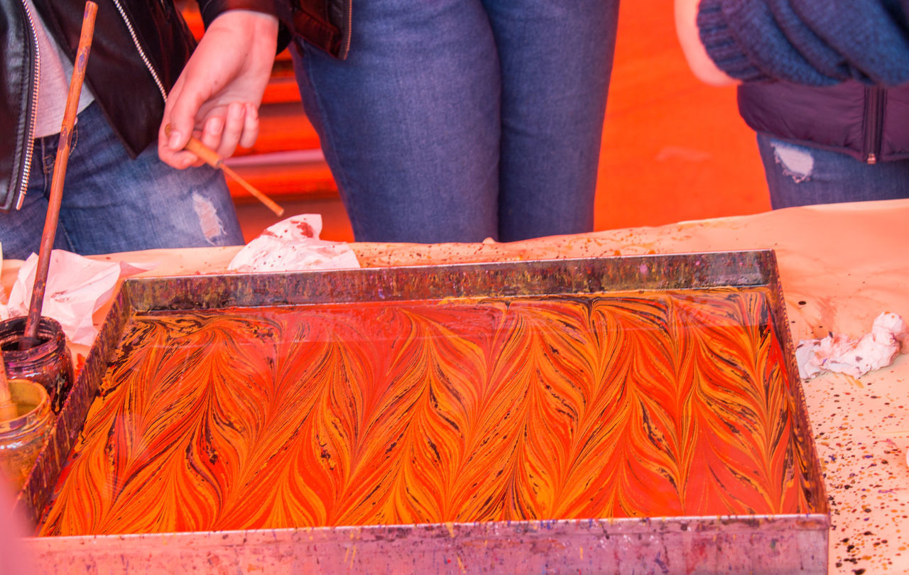 CLOSE-UP OF PEOPLE STANDING AGAINST ORANGE SKY