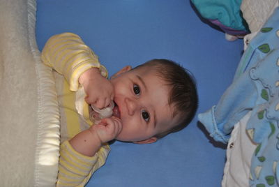 Portrait of cute baby holding pacifier while lying on bed