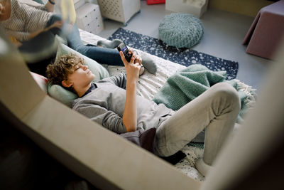 Boy lying on bed wile using smart phone