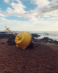 Yellow umbrella on beach against sky