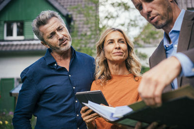 Smiling woman and man having discussion over documents with real estate agent