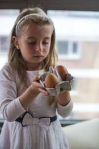 Cute girl holding eggs at home