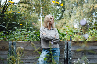 Smiling woman with arms crossed at garden