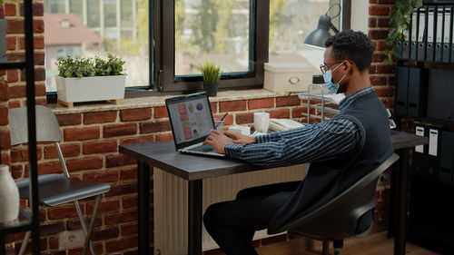 Side view of woman using laptop while sitting on table