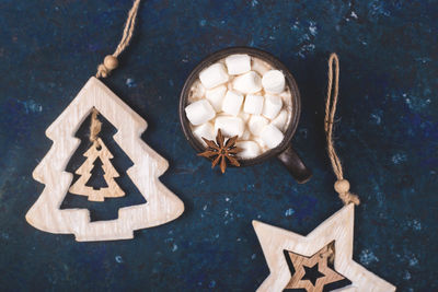 Directly above shot of wooden christmas tree with marshmallow in hot chocolate over abstract background