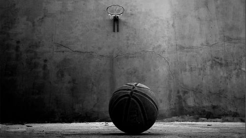 Basketball on floor with hoop hanging on wall