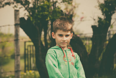 Close-up of boy standing against trees