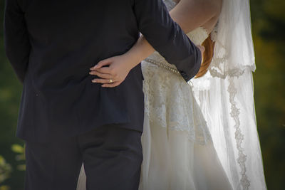 Midsection of bride and groom standing outdoors