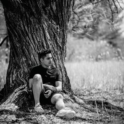 Full length of woman sitting on tree trunk