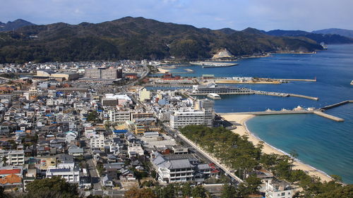 High angle view of city by sea against sky