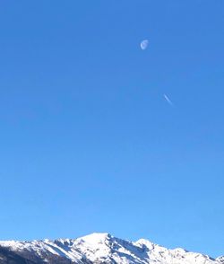 Low angle view of snowcapped mountain against blue sky