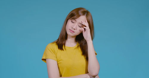 Beautiful young woman standing against blue background