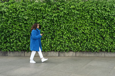 Side view of woman walking by plants