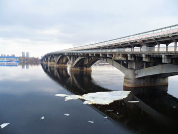 Bridge over river in city against sky
