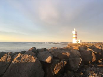 Lighthouse by sea against sky