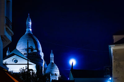 Illuminated building against sky at night in city