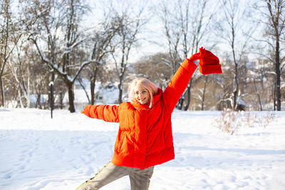Young stylish blonde woman on the street has fun, posing in snowy, frosty