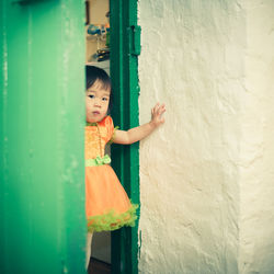 Portrait of baby girl standing at doorway