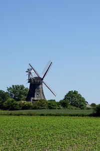 Traditional windmill on field against clear sky