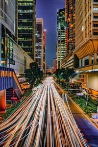 Light trails on road amidst buildings in city at night