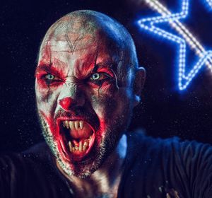 Close-up of man with spooky make-up screaming in darkroom