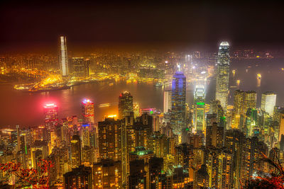 Illuminated modern buildings in city against sky at night