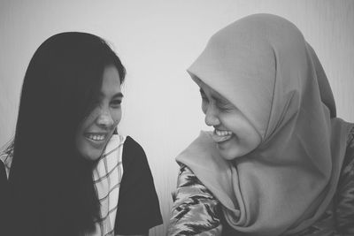 Close-up of smiling friends against wall