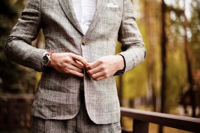 Midsection of well-dressed man standing in park