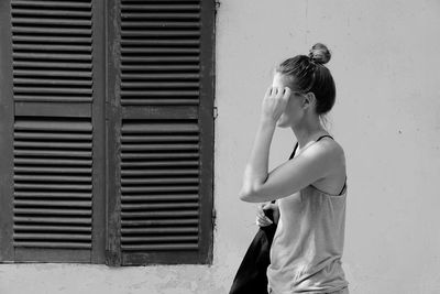 Side view of woman standing against house