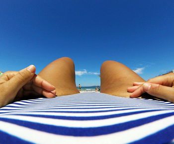 Midsection of woman lying at beach against sky