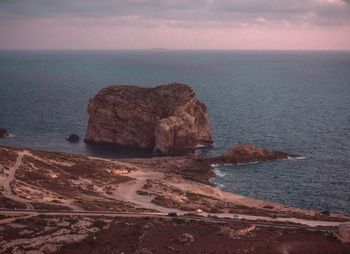 Rock formation on sea shore against sky