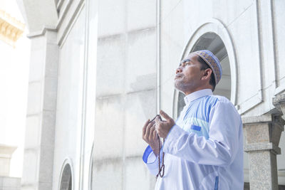 Side view of man looking at camera while standing in building