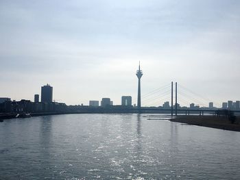 View of suspension bridge over river with city in background