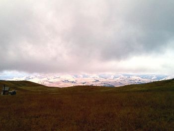 Scenic view of field against cloudy sky