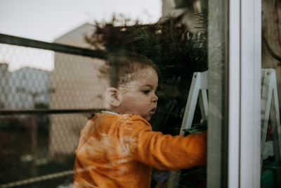 Close-up of cute baby girl seen through glass window