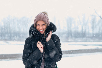 Portrait of smiling young woman standing in snow