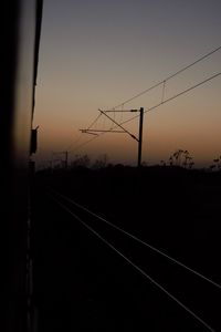 Silhouette railroad tracks against sky during sunset